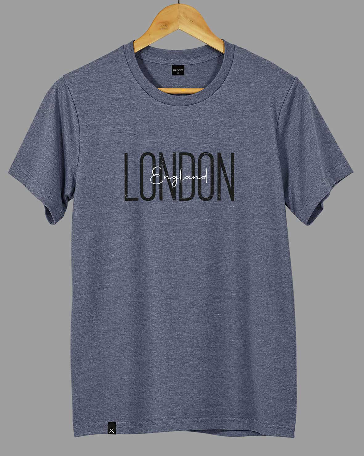 Polera London England gris azulado de BRONX, colgada en percha de madera, con estampado frontal.