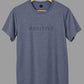 Polera Think Positive gris azulado BRONX colgada en percha de madera, mostrando su diseño frontal.